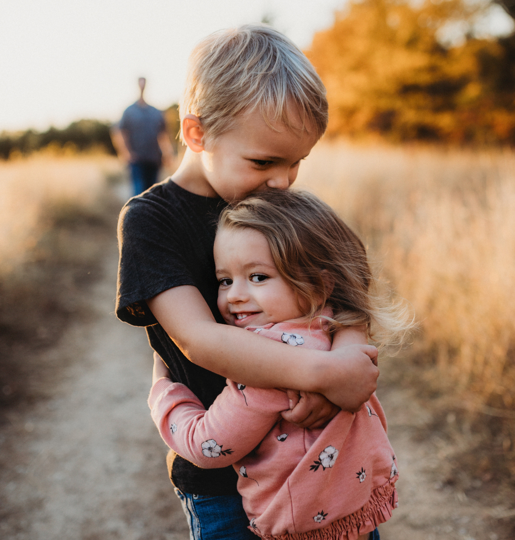 siblings hugging, older sibling kissing younger sibling on head