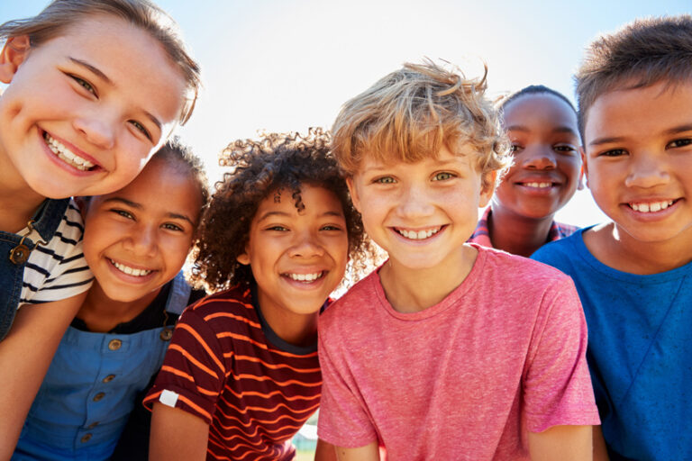 six happy, smiling boys and girls on a bright sunny day