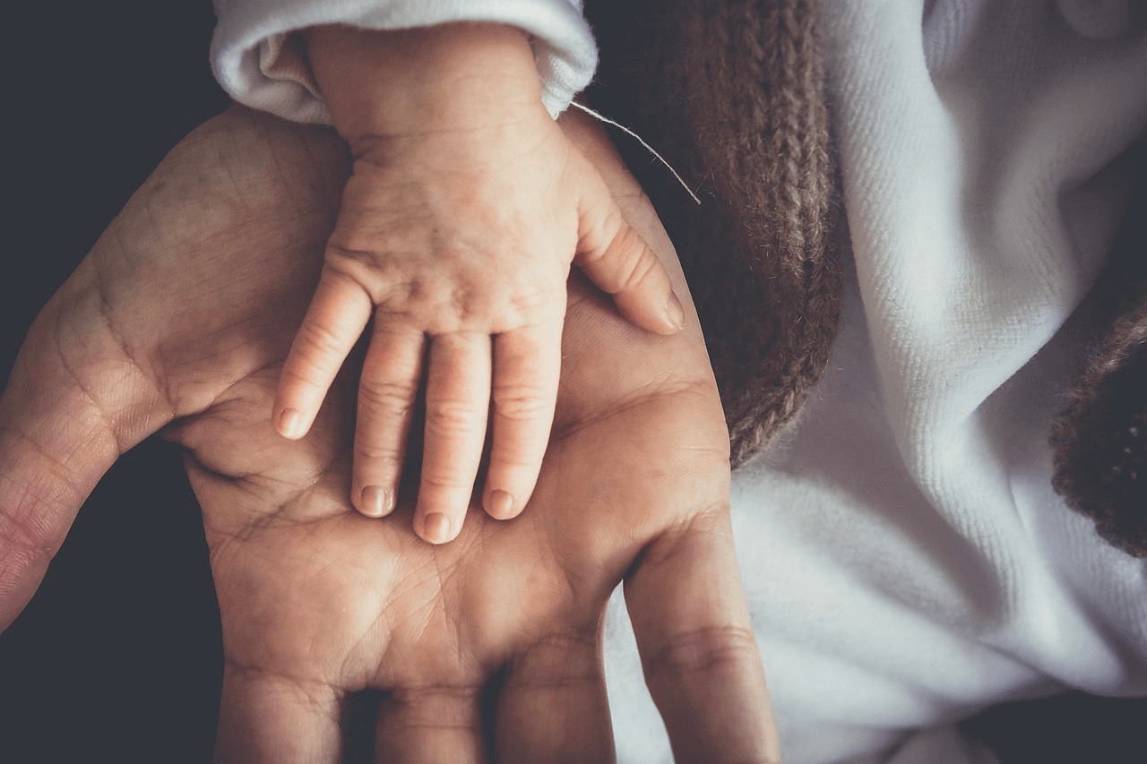 Parenting holding babies hand, protecting child