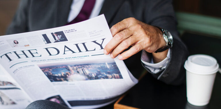Professional man in business suit reading the newspaper and having coffee.