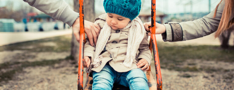 parents and with child on swing between them. all in coats.