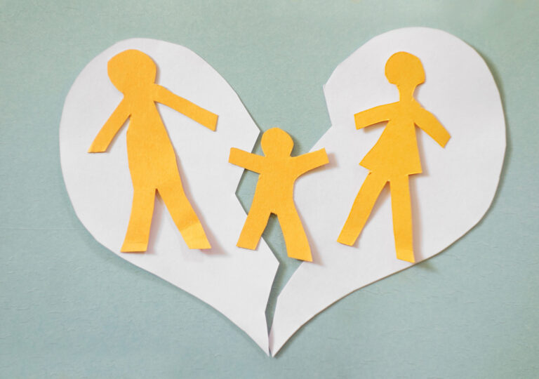 blue background with white paper split heart on top. on top of that are three yellow cut-outs of people, two adults and a child.