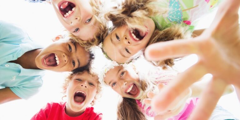 5 kids faces smiling and laughing into camera.