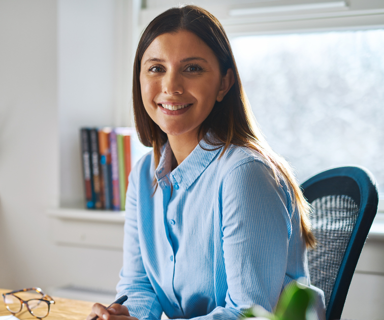 smiling, kind mediator with glasses on desk and books on shelf