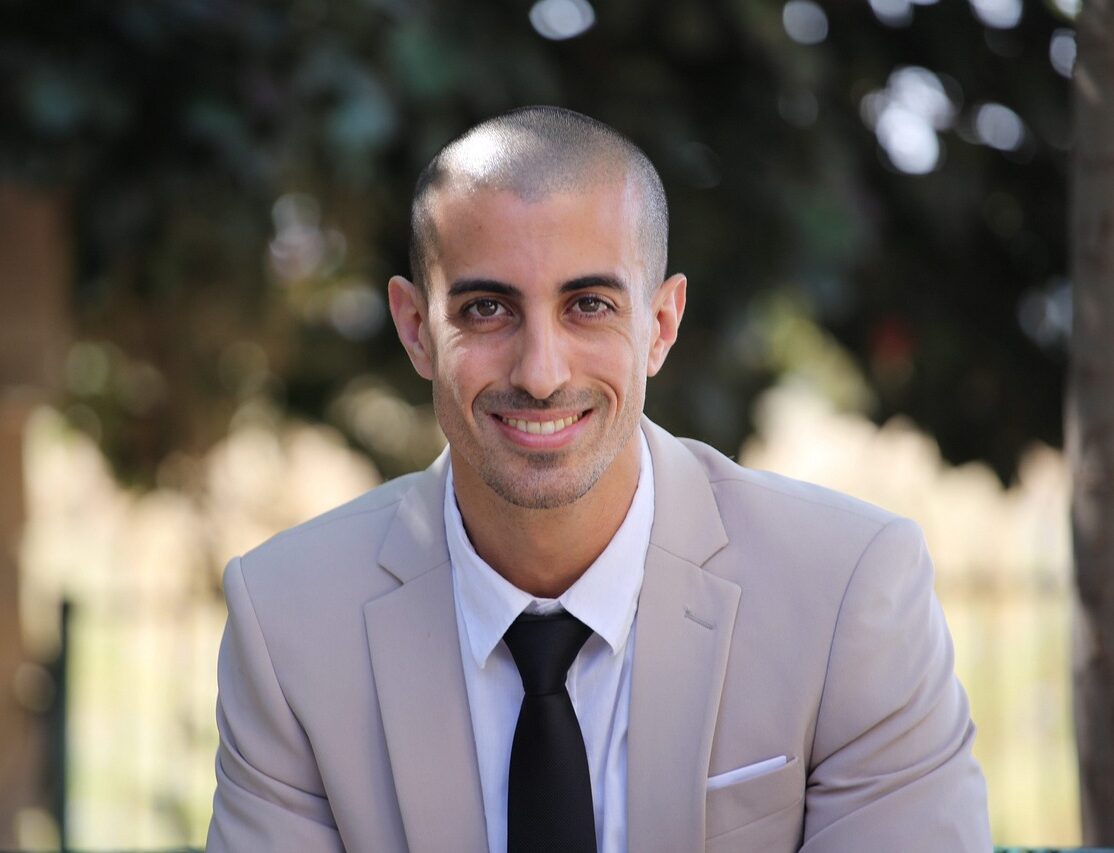 Smiling mediator in suit, outside in front of greenery