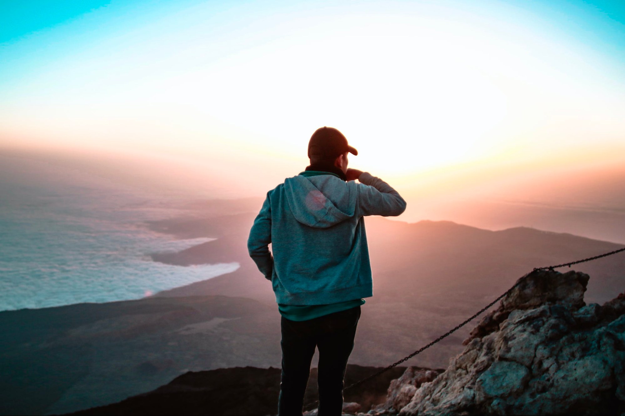 This is an image of someone standing at the top of a mountain, gazing at the view.