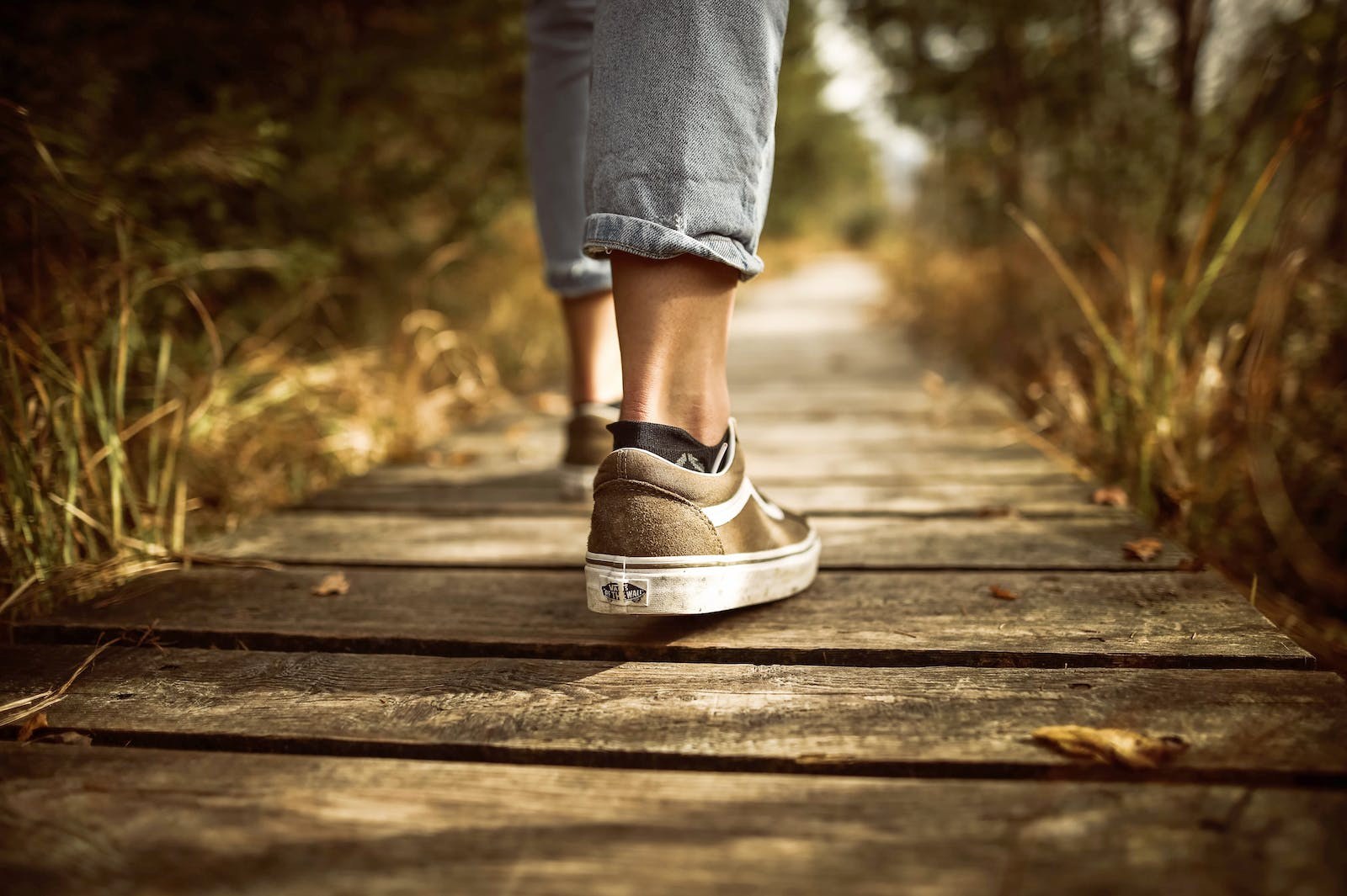 This is an image of a person walking on a wooden pathway.