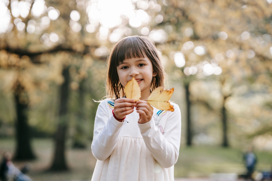 This is an image of a young girl showing off some leaves she picked up.