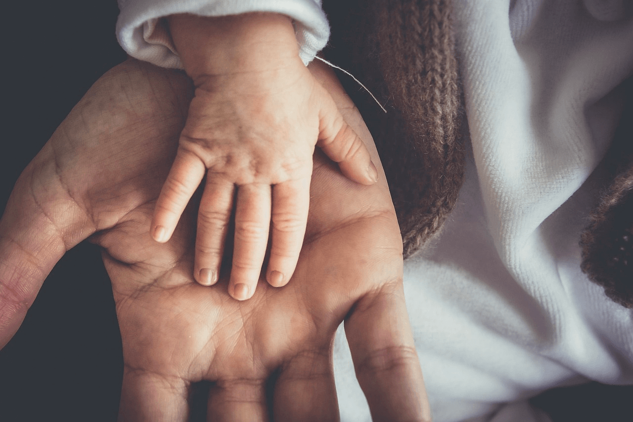 Image of a small child's hand with their father's hand