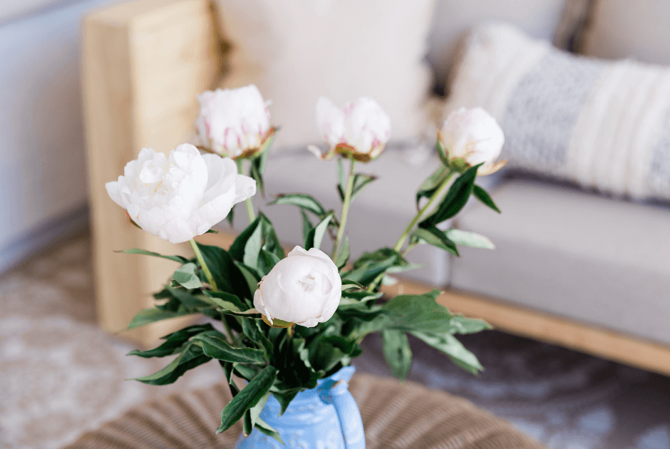 This is an image of a vase with flowers sitting on a coffee table in a living room.