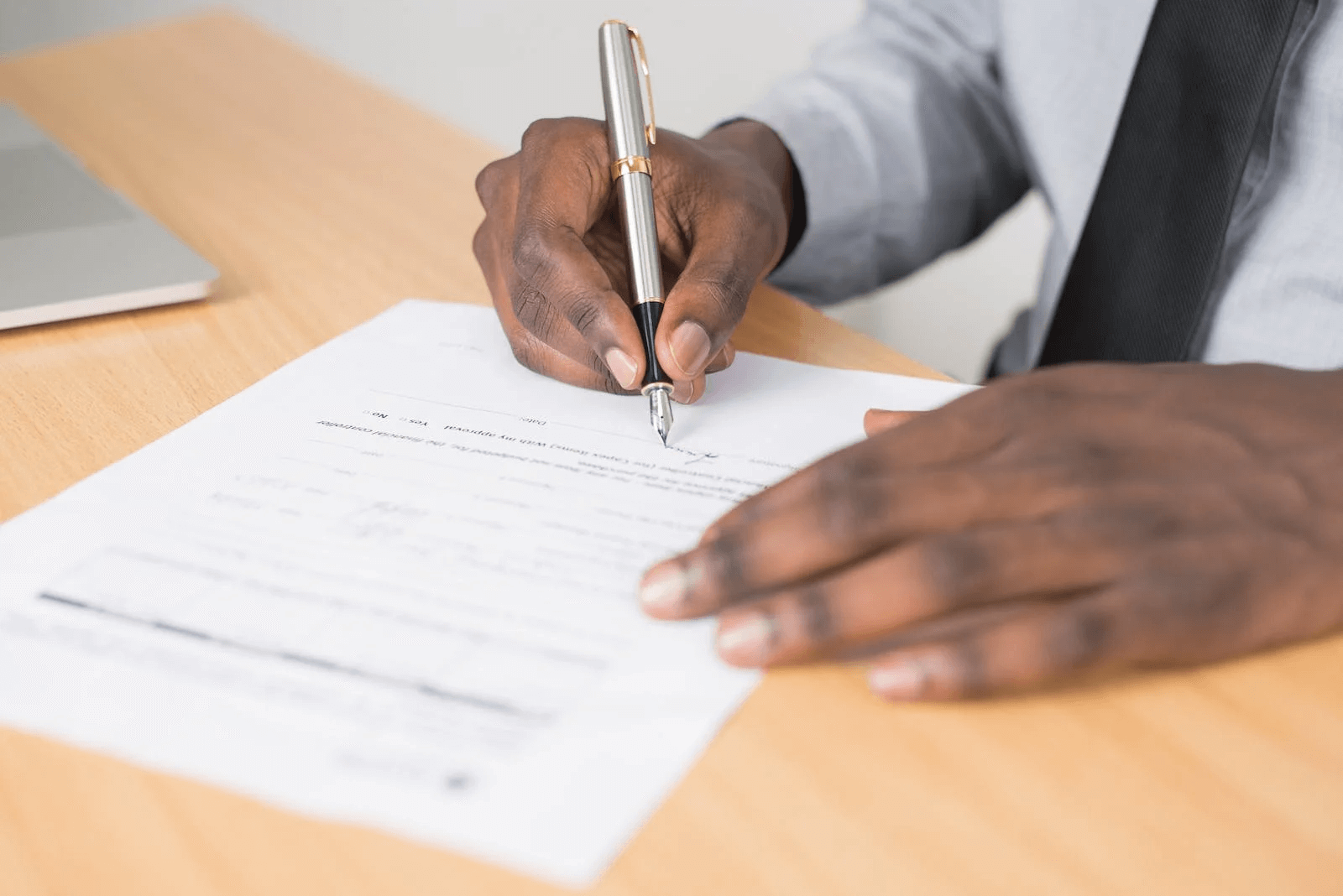 Image of a man's hands as he signs a document
