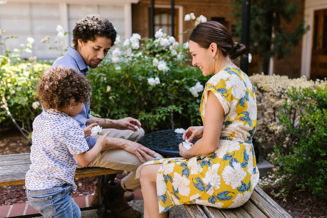 A family of three spends bonding time in a garden.