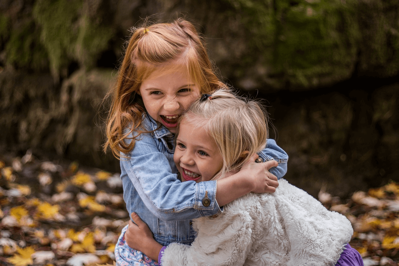 This is an image of two young girls hugging outside