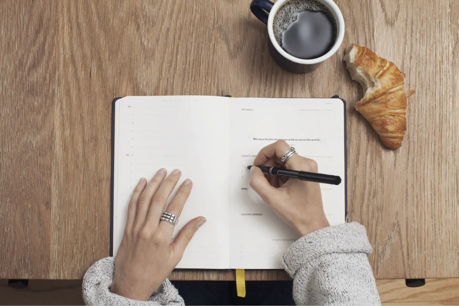 This is an image of a person writing notes with coffee and a pastry.