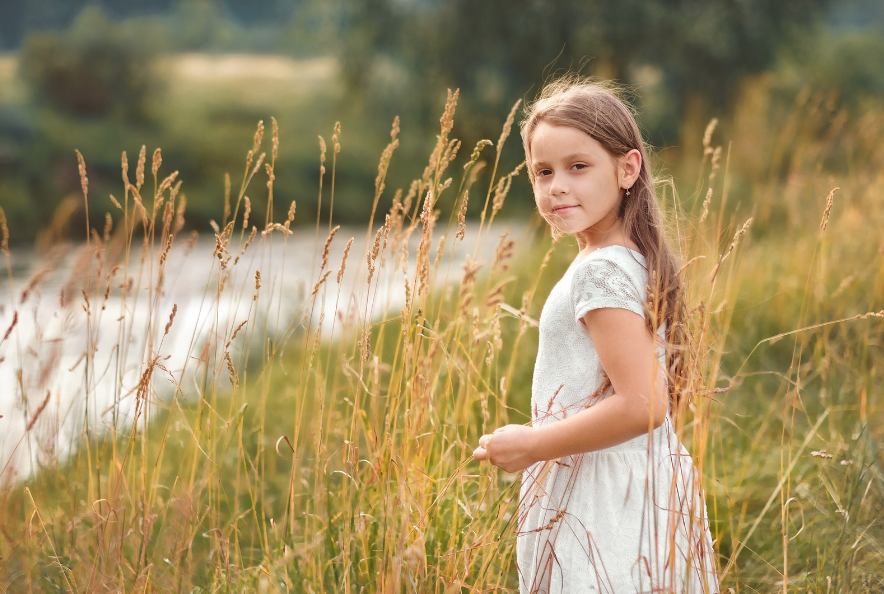 This is an image of a girl looking content, standing near a river.