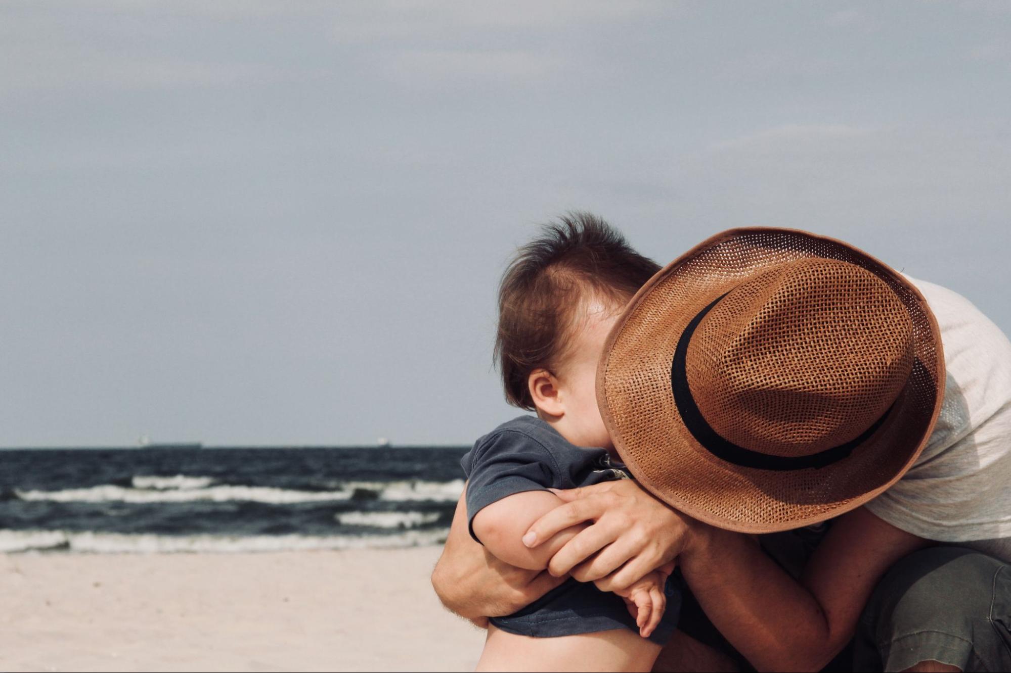This is an image of a father and son embracing on a beach.