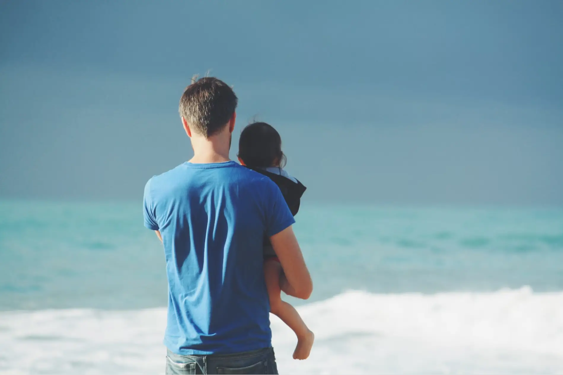 This is an image of a parent holding their child on the beach.