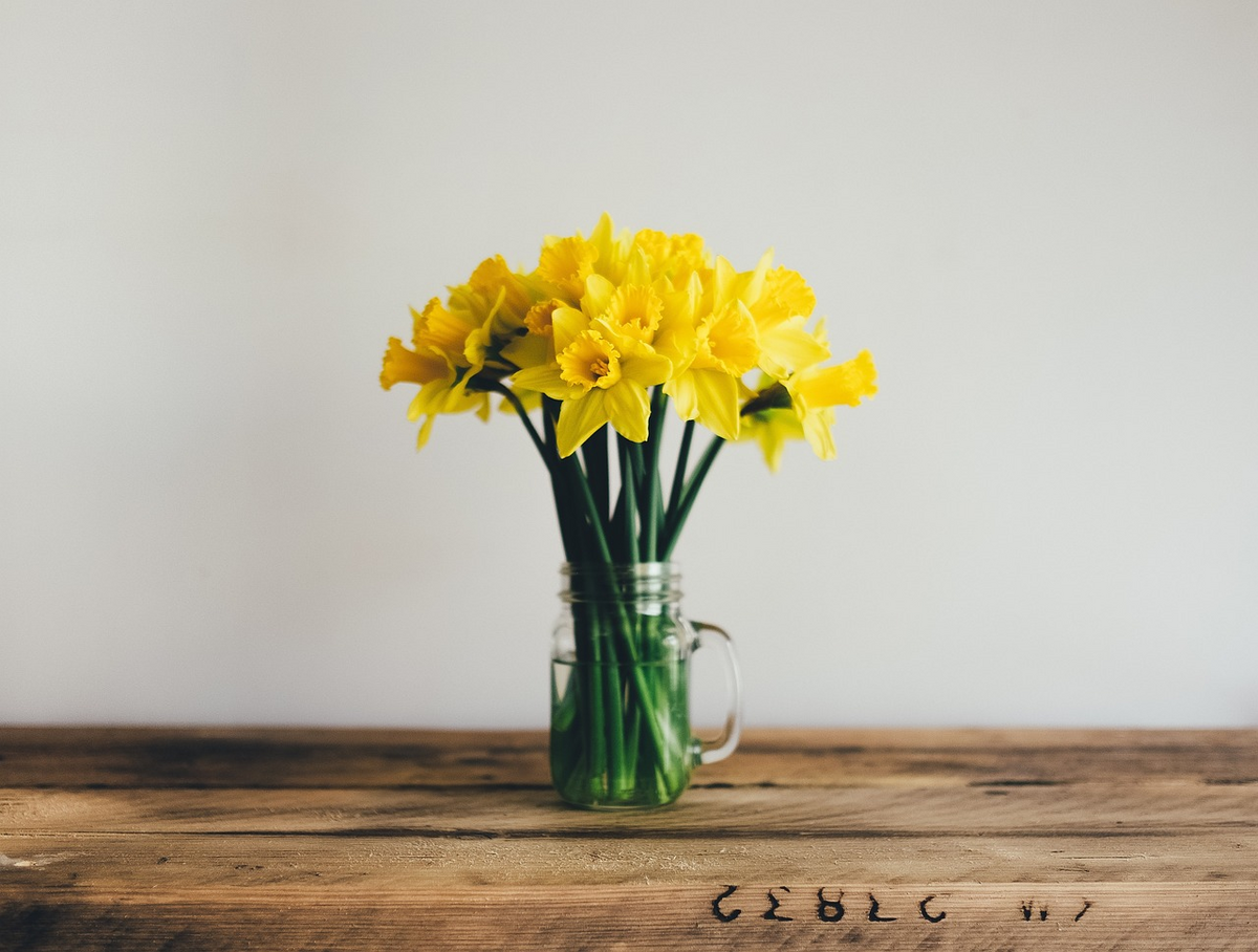 This is an image of a vase of yellow flowers on a table