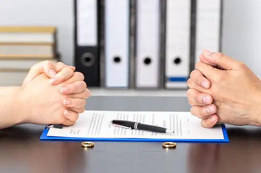 A couple's hands clasped over a divorce document