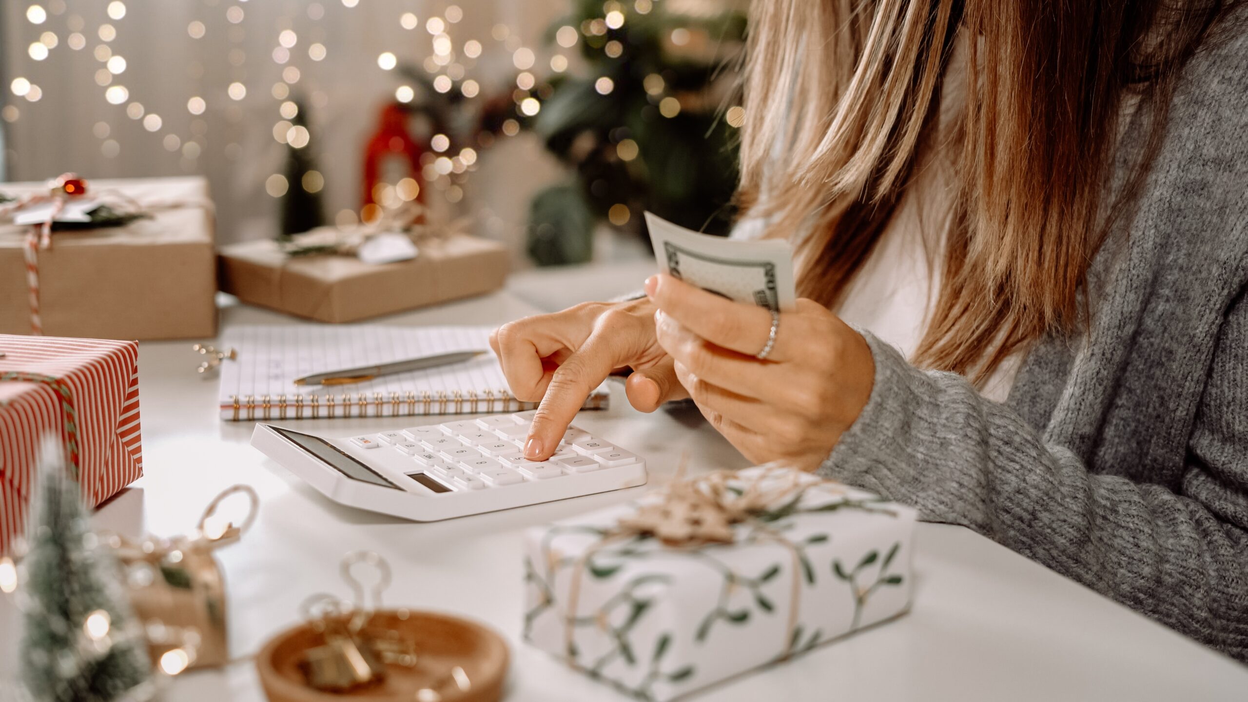 girl,counting,us,dollar,bills,,using,calculator,,and,writing,expenses.